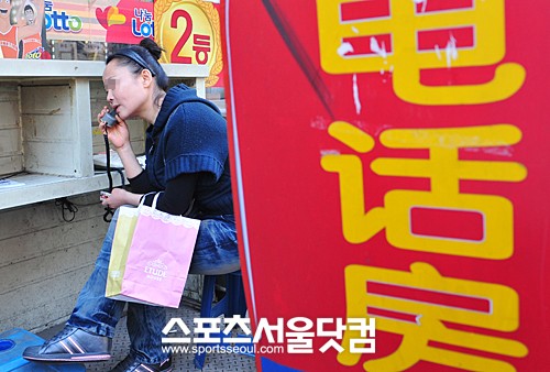 ▲고향 소식을 듣기 위해 전화방을 이용하는 한 조선족 여성.