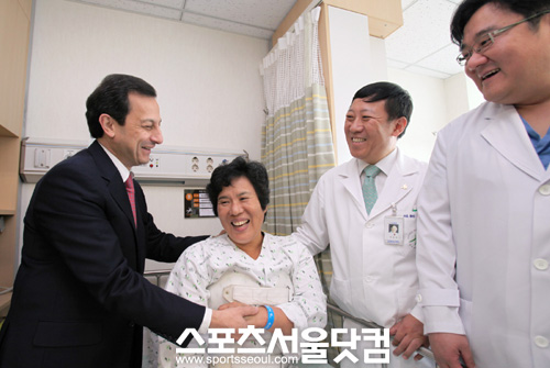 ▲ 22일 마이크 아카몬 한국지엠 사장이 인천의료원에서 환자의 손을 잡고 있다.