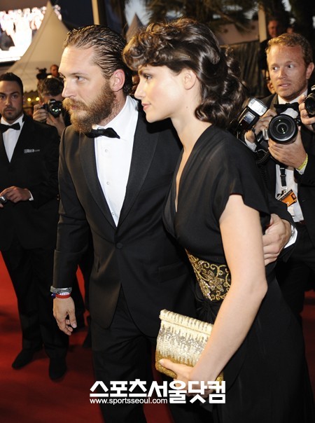 널 위해 선물을 준비했어-배우 톰 하디(왼쪽)가 약혼녀 샬롯 라일리를 취재진 쪽으로 데려가고 있다.