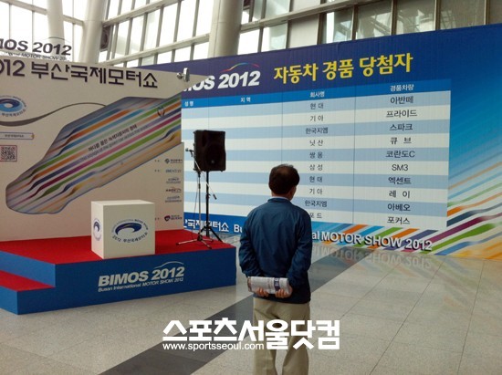한 관람객이 부산모터쇼 자동차 경품 목록을 유심히 바라보고 있다.