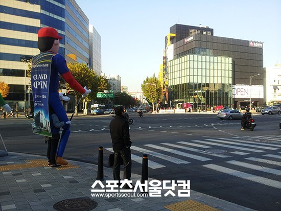삼성 디지털프라자를 홍보하는 직원이 홍보 도구를 들고 LG전자 베스트샵을 바라보고 있다.