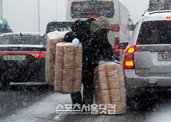서해 5도 지역에 대설주의보가 내려진 5일 오후 인천공항고속도로에서 한 상인이 교통이 정체된 틈을 타 뻥튀기를 팔고 있다. / 조재형 인턴기자