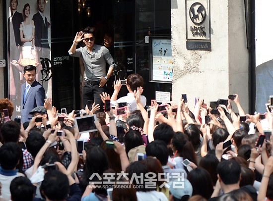 송승헌이 매장 앞 정문에서 팬들에게 손을 흔들고 있다.