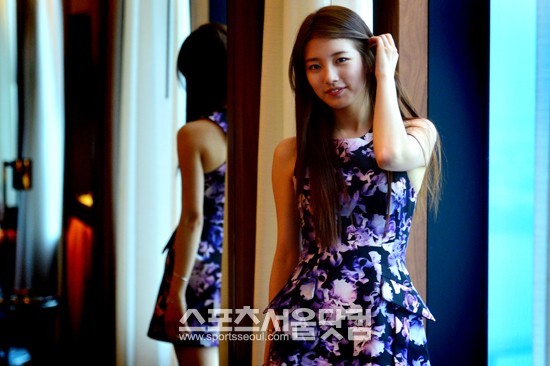 수지가 상큼한 미소를 지으며 머리를 귀 뒤로 넘기고 있다.