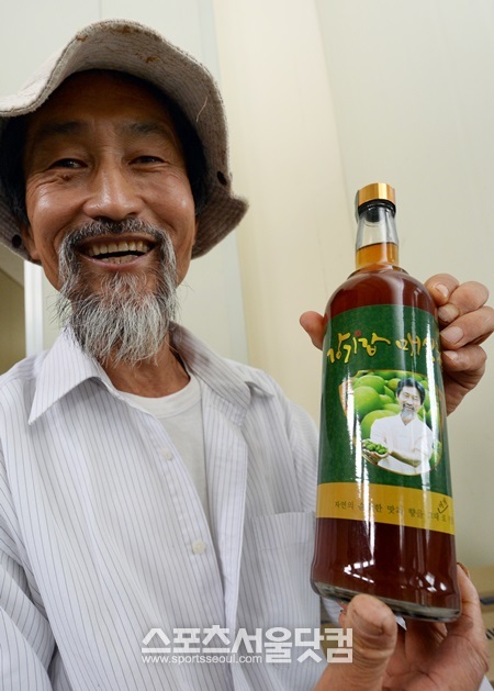 강 전 대표가 자신의 이름과 얼굴이 들어간 매실청을 들고 취재진에게 누가 더 잘 생겼노?라며 농담을 하고 있다.