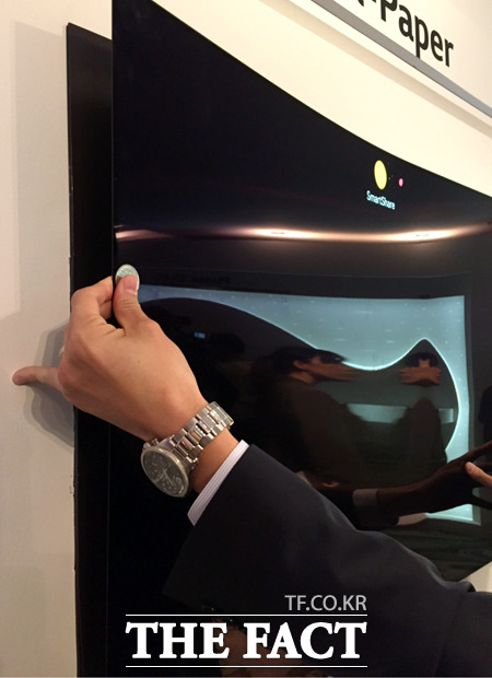 LG디스플레이 직원이 월페이퍼 OLED TV의 두께를 동전 두께와 비교하고 있다.