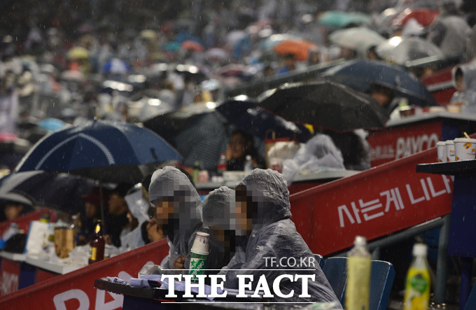 삼성-두산의 한국시리즈 3차전이 우천으로 두 번째 중단되고 있다. 폭우가 쏟아지는 가운데 팬들이 경기 속개를 기다리고 있다.