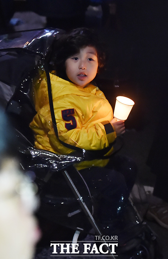 5일 오후 서울 중구 서울광장에서 제2차 민중총궐기 대회가 열린 가운데 행진의 집결지인 서울대학병원 앞에서 한 어린이가 촛불을 들어보이고 있다.