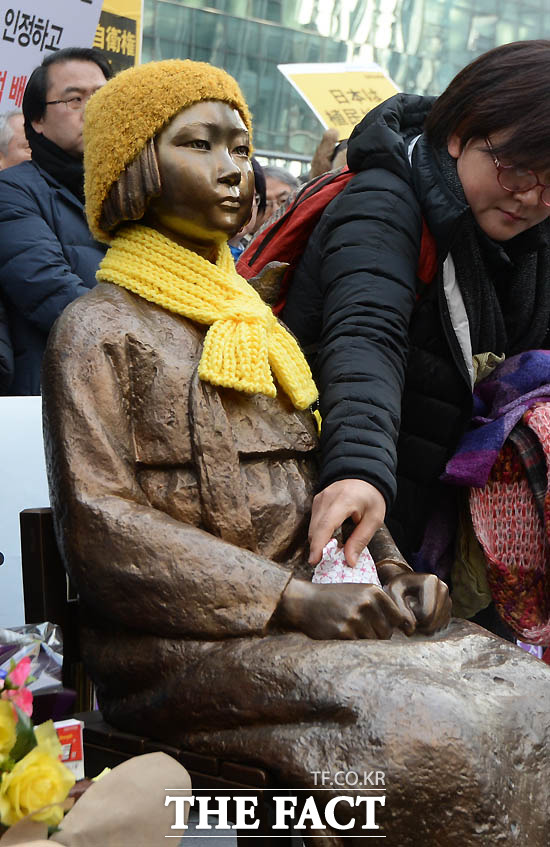 한 시민이 소녀상 무릎 위에 핫팩을 놓고 있다.