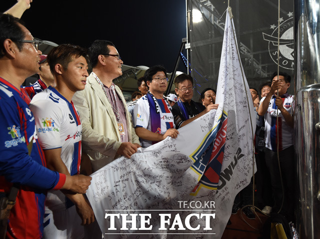 깃발전쟁에서 승리한 수원FC 깃발이 성남 홈구장에 걸리고 있다. 염태영, 이재명 시장이 깃발을 올리고 있다.