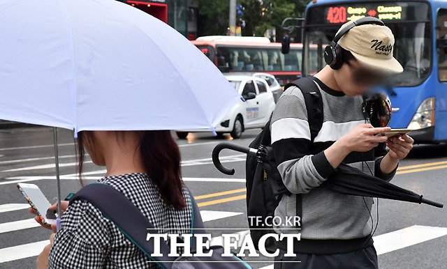 비가 내려 우산을 써도 스마트폰을 합니다.