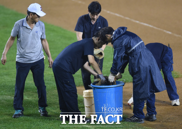 6회초 우천으로 경기가 중단되자 관리원들이 빗물 제거를 하고 있다.