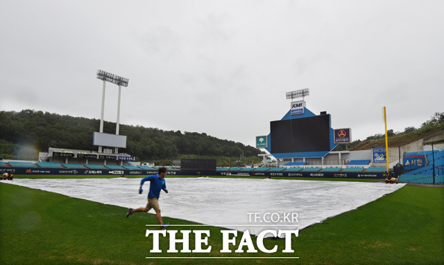롯데-삼성의 경기가 우천으로 취소된 가운데 경기장 관리요원이 비가 쏟아지지는 그라운드 위에서 방수포를 점검하고 있다.
