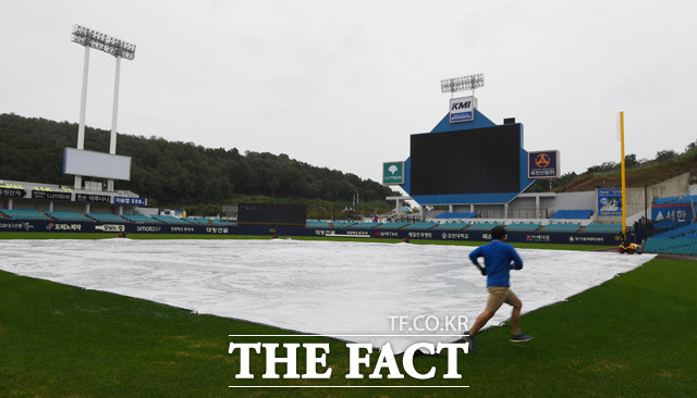 롯데-삼성의 경기가 우천으로 취소된 가운데 경기장 관리요원이 비가 쏟아지지는 그라운드 위에서 방수포를 점검하고 있다.