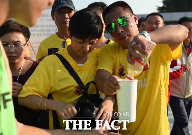 중국 응원단이 경기장 입장하다 경비요원의 요청에 음료수를 컵에 따르고 있다. 음료수병은 반입 금지다.