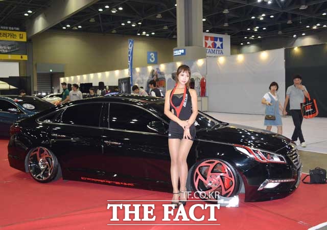 레이싱 모델이 튜닝카 앞에서 포즈를 취하고 있다.