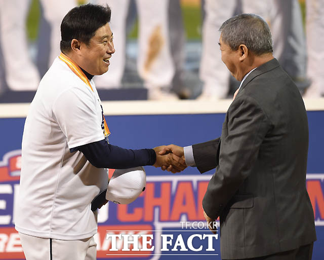 두산 김태형 감독이 구본능 총재와 악수를 나누며 환하게 웃고 있다.