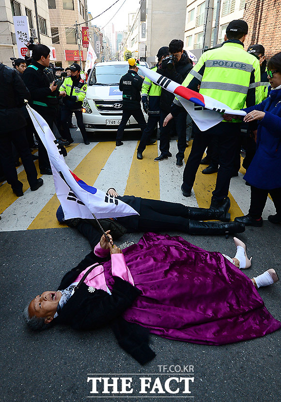 보수단체 회원들이 박근혜 전 대통령 사저 앞 도로에 누워 종편채널 JTBC 취재차량 통행을 방해하고 있다.