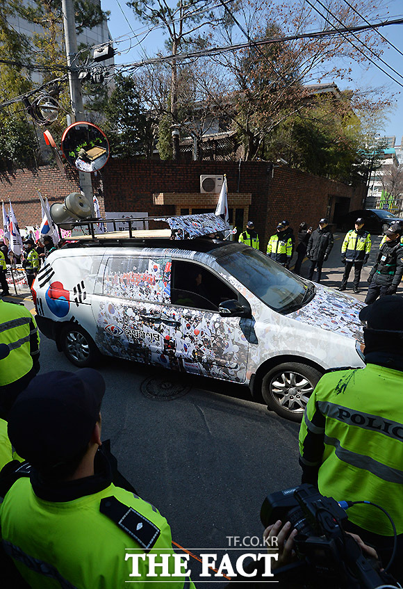 태극기 무늬로 장식한 보수단체 차량이 박근혜 전 대통령 사저 앞을 지나가고 있다.