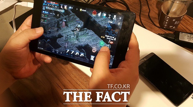 한 게임 이용자가 스마트폰을 책상에 놓아둔 채 태플릿PC로 리니지M을 즐기고 있다.