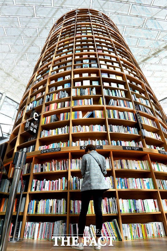 코엑스 별마당 도서관을 찾은 한 시민이 첨탑 처럼 쌓인 책들 아래서 독서를 하고 있다.