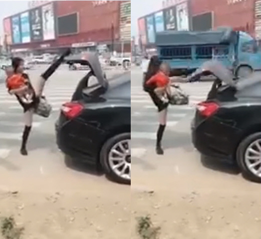 한 여성이 한 손에 짐과 다른 한 손에 아이를 안은 채 다리로 자동차의 트렁크를 닫고 있다. /유튜브 캡처