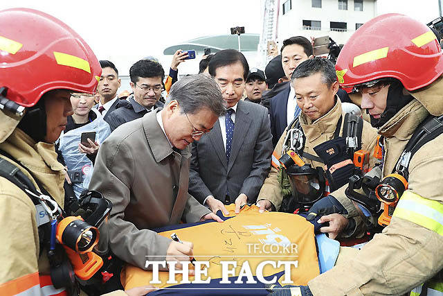 3일 충남 천안 소방학교에서 열린 소방의 날 행사에 참석한 문재인 대통령이 행사를 마친 후 소방관옷에 사인을 해주고 있다. /청와대 제공