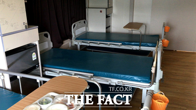 병실내에는 침구류도 갖춰지지 않은 빈 침대들이 놓여 있다. 서류상의 입원 환자의 자리로 추정된다.