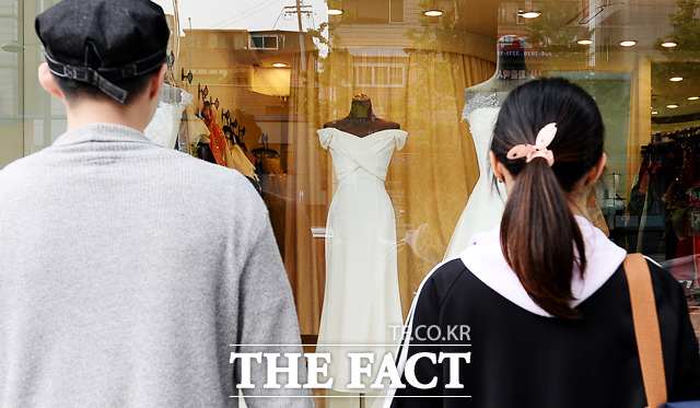 부부의 날인 21일 오후 서울 서대문구 아현동 일대 웨딩거리를 찾은 커플이 웨딩드레스를 구경하고 있다. /이선화 기자