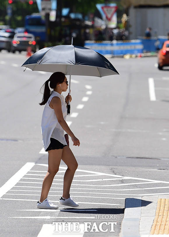 큰 우산으로 자외선을 피하는 한 시민
