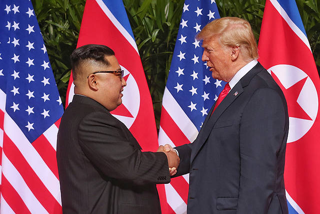 김정은 북한 국무위원장(왼쪽)과 트럼프 미국 대통령이 12일 오전 싱가포르 센토사섬 카펠라호텔에서 정전 65년 만에 열린 북미정상회담에 참석해 악수를 하고 있다. / 싱가포르 통신정보부