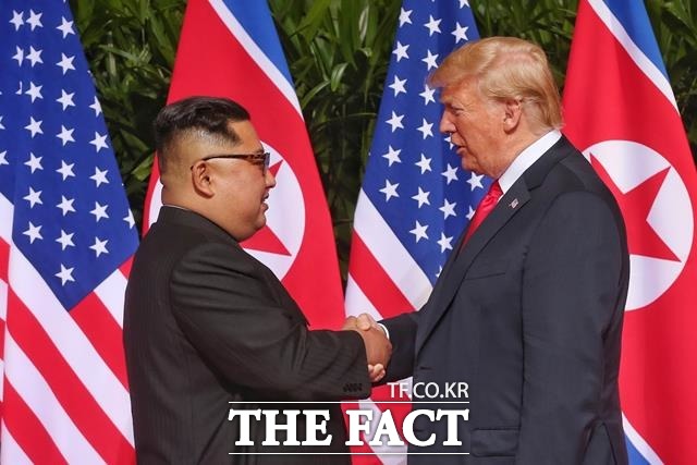 김정은(왼쪽) 북한 국무위원장과 도널드 트럼프(오른쪽) 미국 대통령이 12일(현지시간) 싱가포르 카펠라 호텔에서 만나 악수를 나누고 있다./ 싱가포르 통신정보부 제공