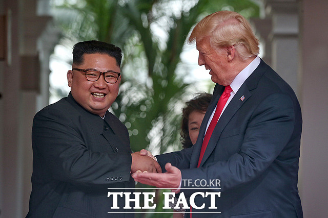 트럼프 대통령과 악수하며 활짝 웃고 있는 김정은 위원장. /싱가포르 통신정보부 제공