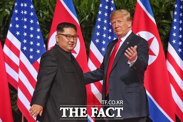 김정은 위원장(왼쪽) 트럼프 대통령이 회담장소인 싱가포르 카펠라 호텔에서 만나 악수를 나누고 있다./ 싱가포르 통신정보부 제공