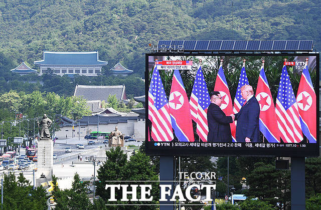 김정은 북한 국무위원장(왼쪽)과 트럼프 미국 대통령이 12일 오전 싱가포르 센토사섬 카펠라호텔에서 정전 65년 만에 열린 북미정상회담에서 악수하는 모습에 세계가 환호했다. 사진은 이날 서울 세종대로의 대형 화면 뒤로 청와대의 모습. /배정한 기자