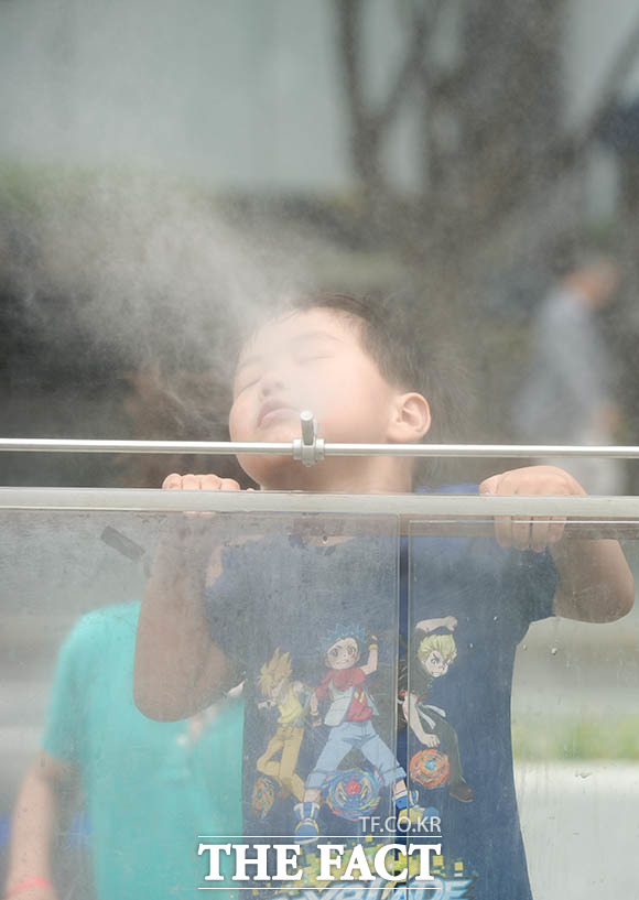 서울의 낮 최고기온이 28도까지 오르며 여름 날씨를 보인 17일 오후 서울 종로구 광화문광장을 찾은 한 어린이가 보행로에 설치된 쿨스팟 앞에서 더위를 식히고 있다.<br> /김세정 기자