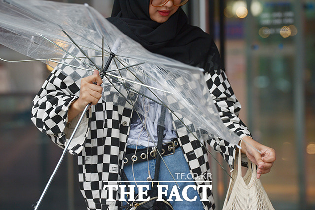 장마의 영향으로 전국에 비가 내리는 가운데 26일 오전 서울 마포구 상암동 인근에서 한 외국인이 비바람에 망가진 우산을 정리하고 있다, /이선화 기자