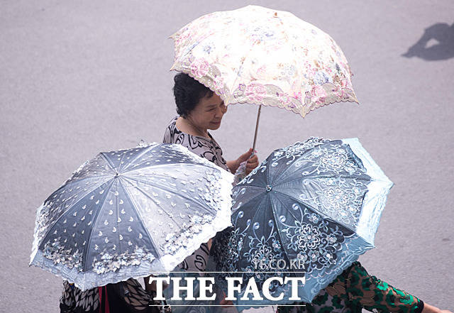 4일 오전 평양 고려 호텔 앞으로 주민들이 양산을 쓰고 지나가고 있다.