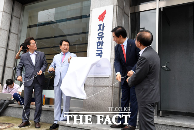 한국당 새 당사에서 열린 현판식은 홍준표 전 대표의 떠들썩한 출국에 비해 조촐하게 진행됐다. 사진은 현판을 가린 천막을 걷어내는 당직자들 모습. /남윤호 기자