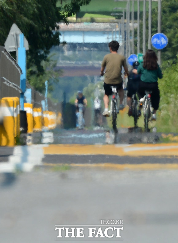 폭염경보가 발령된 16일 오후 서울 한강공원 잠원지구에서 시민들이 자전거를 타고 있는 아스팔트 위로 아지랑이가 올라오고 있다. /이효균 기자