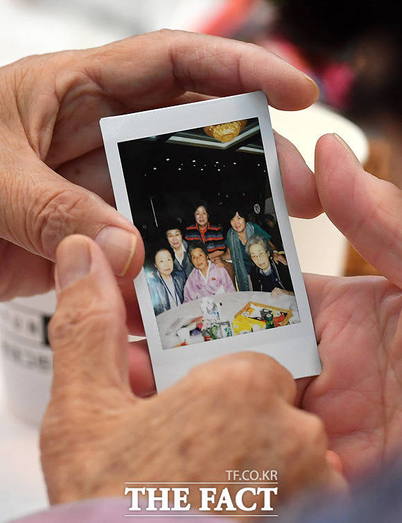 남측 언니 양순옥(86)씨와 북측 동생 량차옥씨 등 육자매 이산가족이 다같이 촬영한 기념사진을 보고 있다.