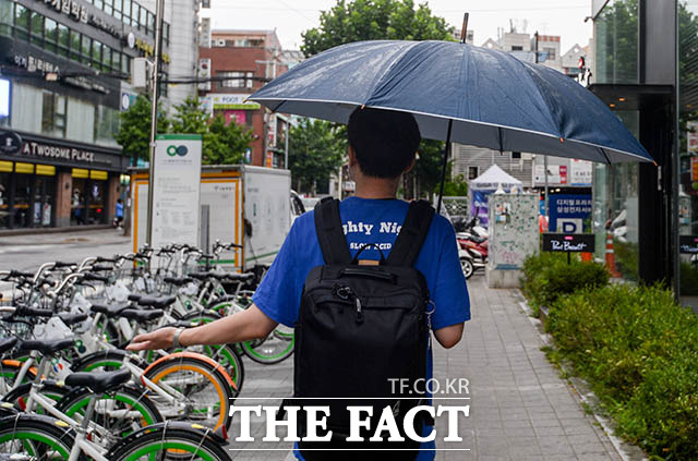 전국 곳곳이 흐리고 비가 내리는 3일 오전 서울 마포구 동교동 한 거리에서 시민이 우산을 쓴 채 비가 오는지 확인하고 있다. /김세정 기자