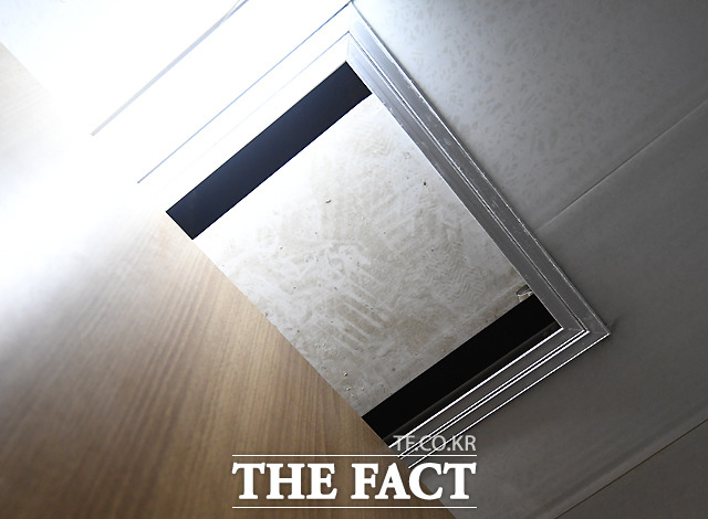 화장실의 칸막이 위로 천장 틈이 벌어져 보이고 있다.