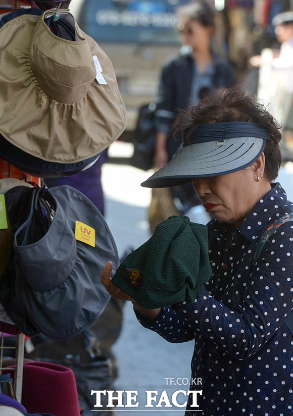 서울 지역 기온이 13.8도 까지 떨어지며 선선한 가을 날씨를 보이는 27일 오전 서울 중구 남대문시장의 한 모자가게에서 여름용 모자를 쓴 한 시민이 가을용 모자를 고르고 있다. /김세정 기자