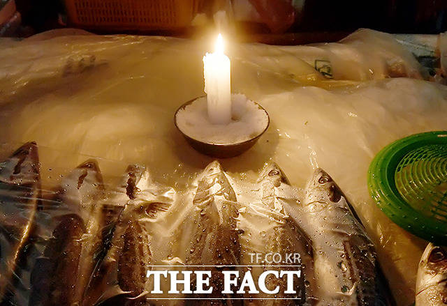 촛불 하나가 생선 좌판을 밝힙니다.