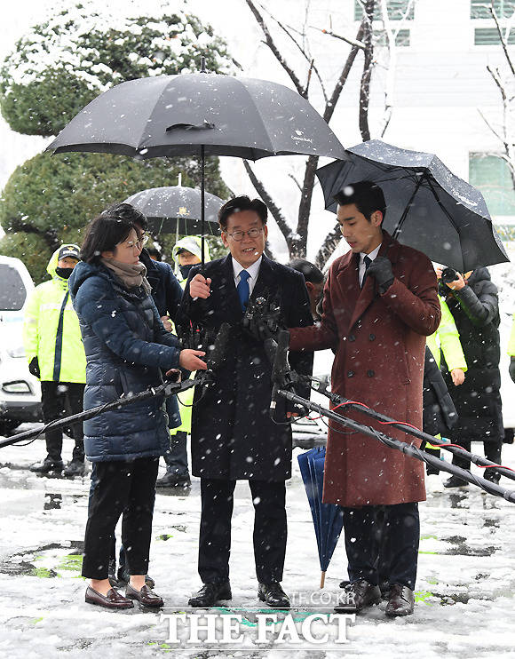 우산 들고 취재진의 질의에 대답하는 이 지사