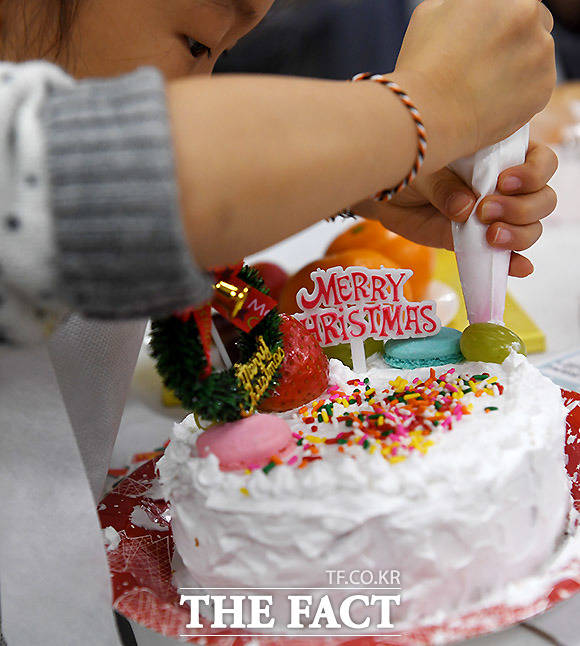 케이크에 데코레이션 하는 한 어린이
