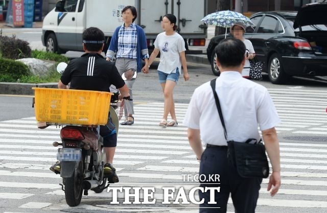 서울의 한 도로에서 헬멧을 착용하지 않은 오토바이 운전자가 횡단보도를 가로지르고 있다. /더팩트 DB