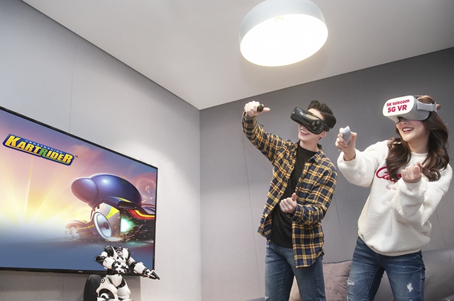 SK텔레콤은 19일 넥슨과 5G VR 게임 개발을 위한 인기 온라인게임 3종의 IP 사용 계약을 체결했다고 밝혔다. 모델들이 VR기기를 쓰고, 카트라이더 게임 화면을 시청하고 있다. /SK텔레콤 제공