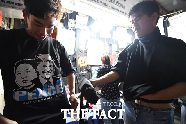 일본인 관광객들이 24일(현지 시간) 길거리 옷가게에서 판매하는 김정은-트럼프 티셔츠를 입어보고 있다. /하노이(베트남)= 임세준 기자